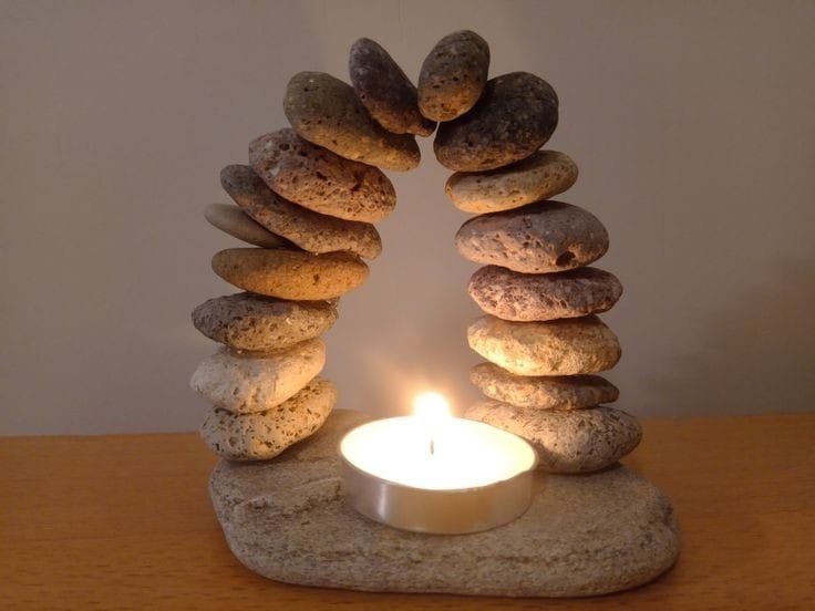 a lit candle sitting in front of rocks stacked on top of each other