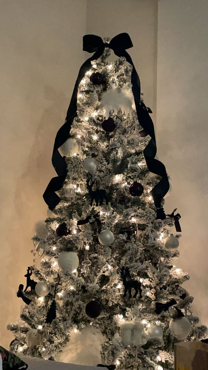 a white christmas tree with black bows and ornaments