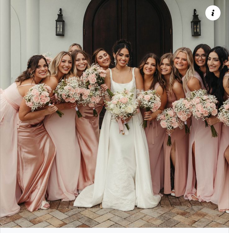 a group of women standing next to each other in front of a door holding bouquets