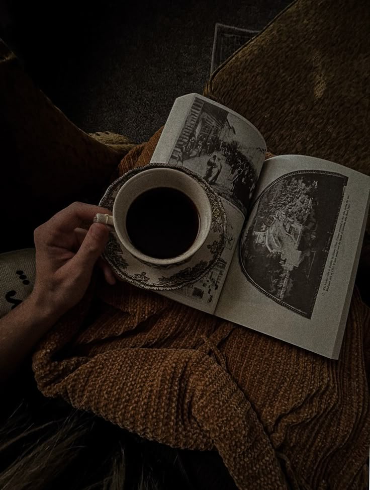 a person holding a coffee cup and reading a book