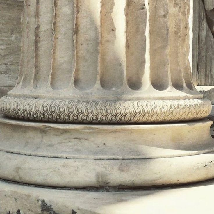 a cat is sitting on the base of a column