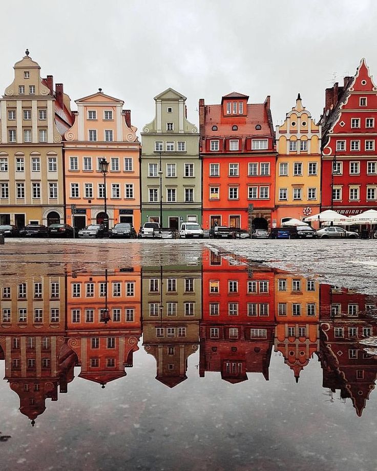 many buildings are reflected in the water on a cloudy day with no one around them