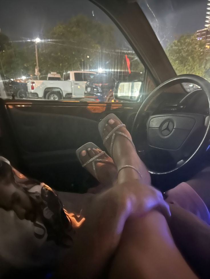 a person sitting in the driver's seat of a car with their feet on the steering wheel