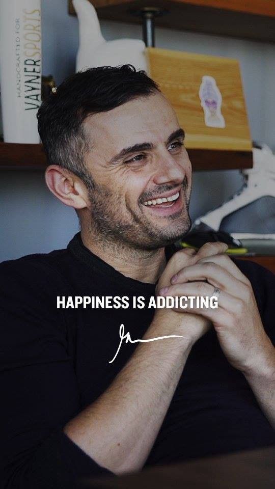 a man smiling while sitting in front of a book shelf with a quote on it