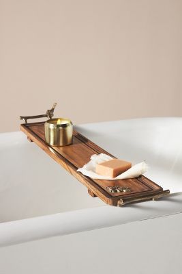 a bathtub with soap and other items on the edge, including a wooden tray