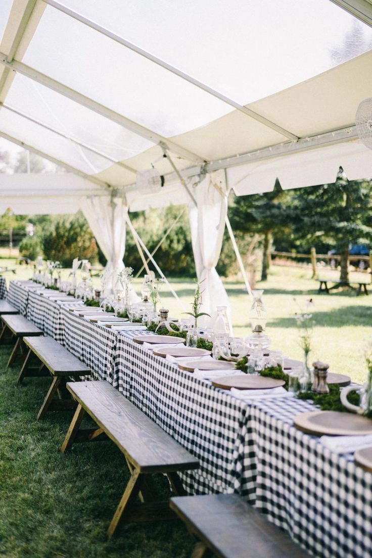 a long table with black and white checkered cloths under a tented area