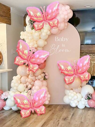 the balloon arch is decorated with pink and white balloons, which are shaped like butterflies