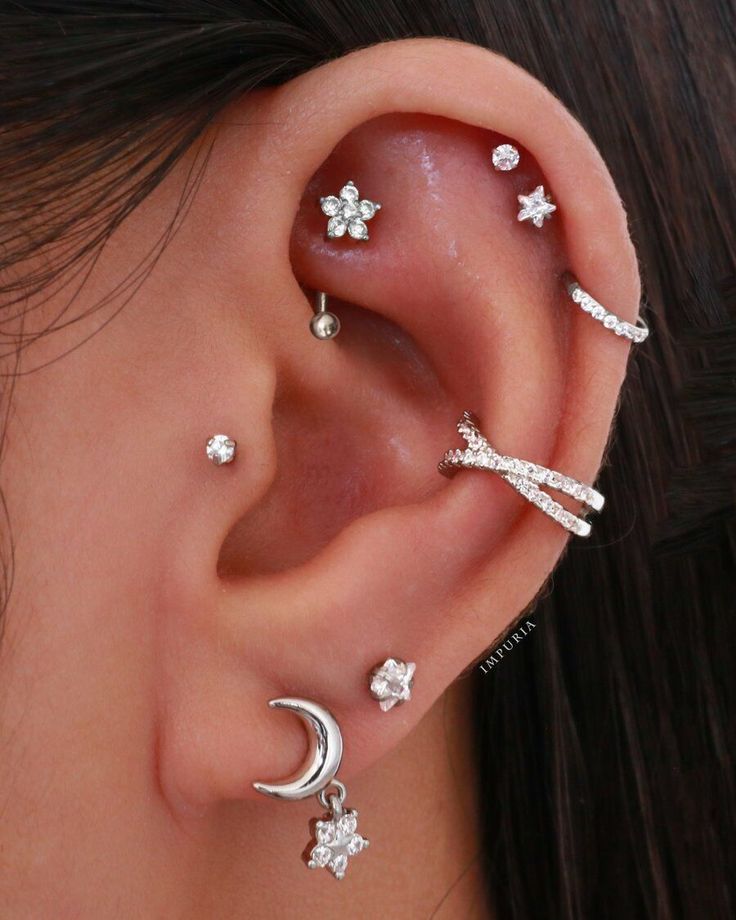 a woman wearing three different ear piercings with stars and moon designs on their ears