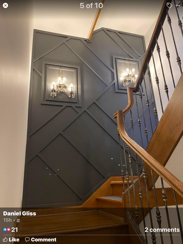 a staircase with chandeliers on the wall next to a wooden banister and handrail