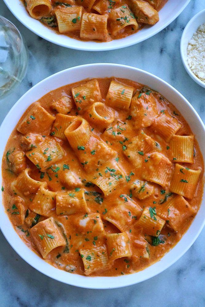 two bowls filled with pasta and sauce on top of a marble table next to rice