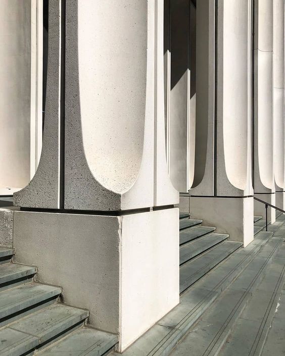 some white pillars and steps in front of a building with columns on each side that are lined up against the wall