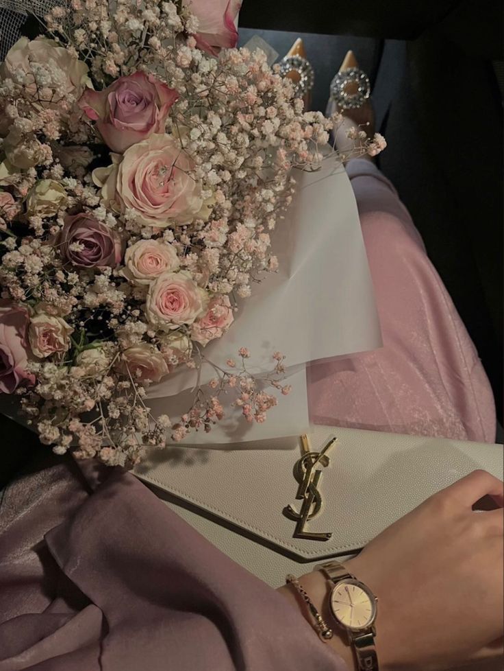 a bouquet of flowers sitting on top of a table next to a watch and purse