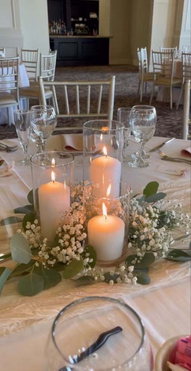 the table is set with white candles and greenery for an elegant touch to the centerpiece