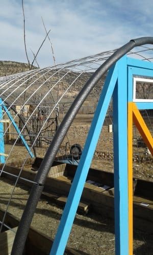 a blue and yellow structure sitting in the middle of a field with other metal structures