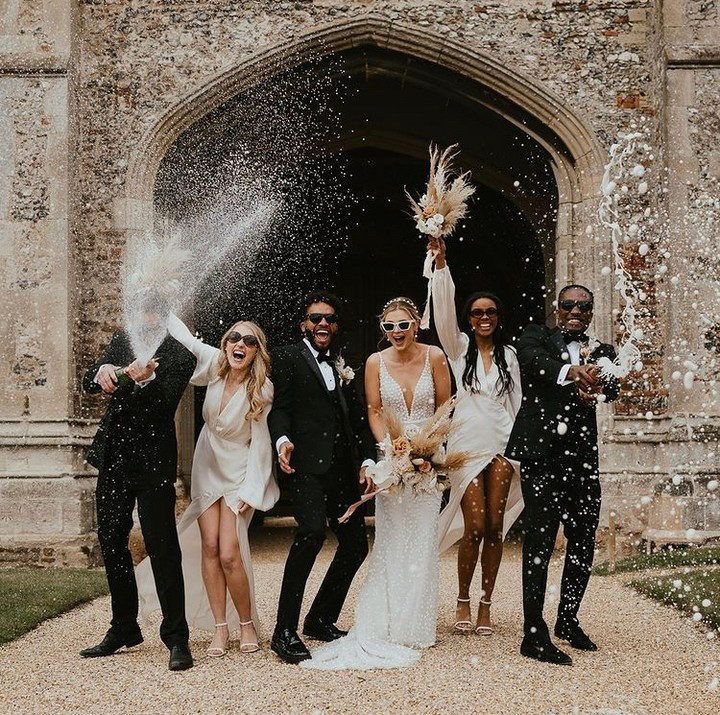 a group of people standing next to each other in front of a building with confetti