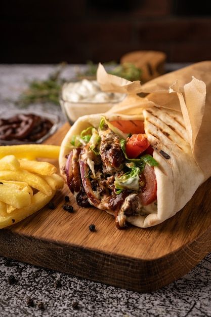 a burrito and fries on a cutting board