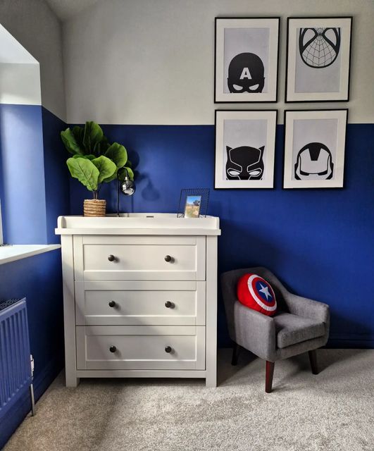 a bedroom with blue walls and pictures on the wall next to a dresser in front of a window