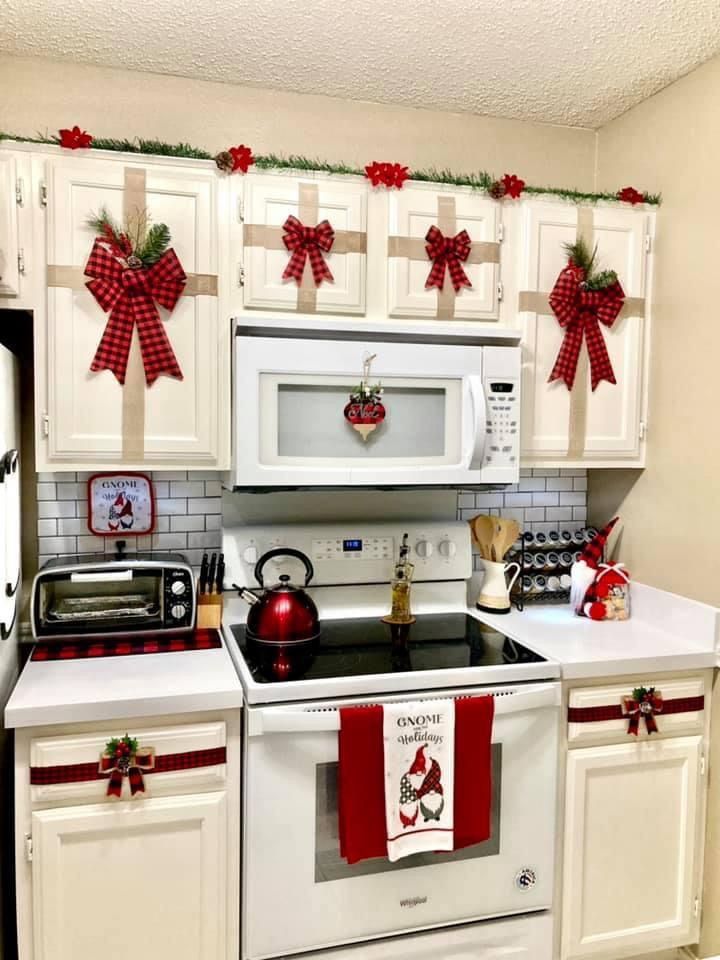 a kitchen decorated for christmas with red and white bows on the cabinets, stove top oven and microwave