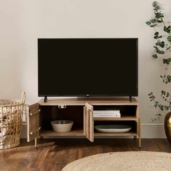 a flat screen tv sitting on top of a wooden entertainment center next to a plant