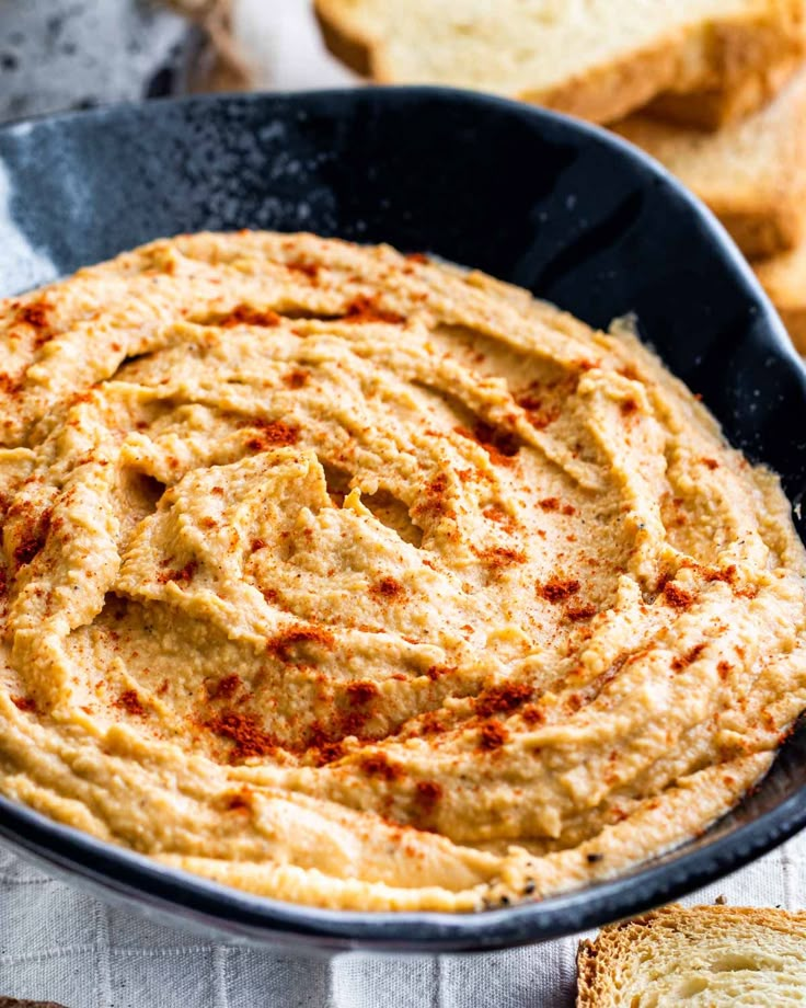 a pan filled with hummus and bread slices