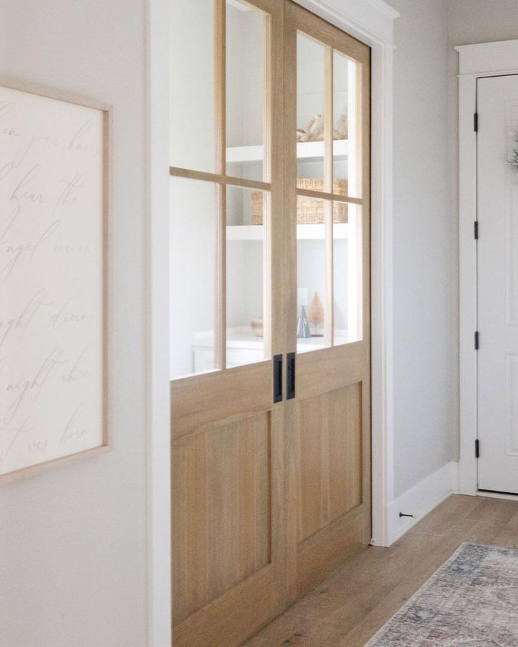 a white room with wooden doors and a rug on the floor in front of it