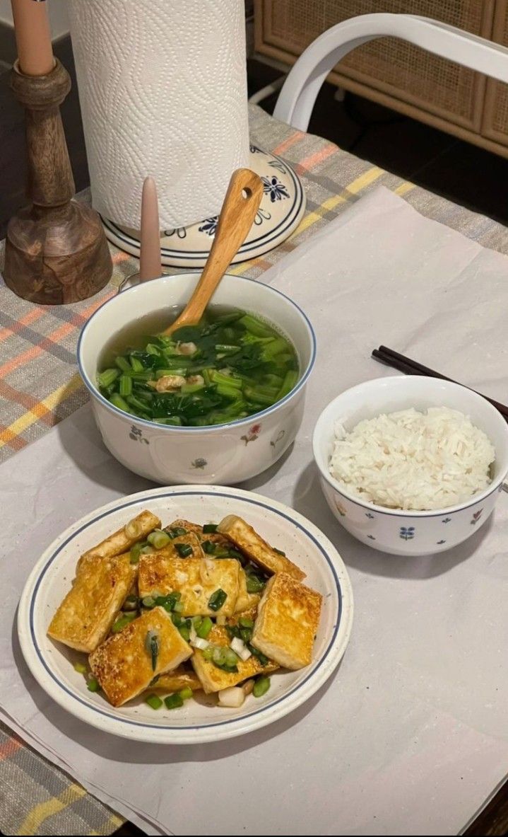 a table topped with bowls and plates filled with food next to a bowl of rice