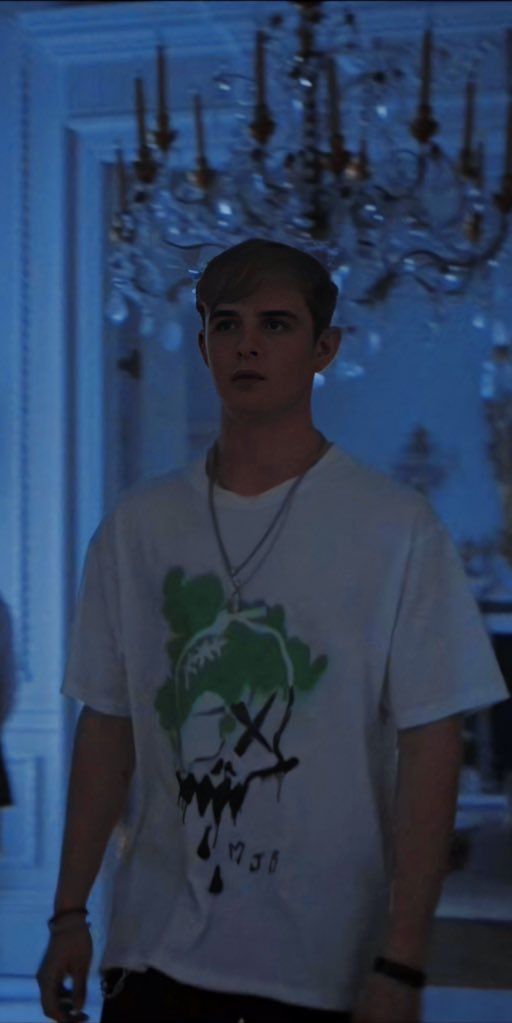 a young man standing in front of a chandelier