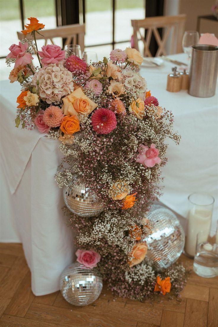 a vase filled with lots of flowers sitting on top of a table next to disco balls