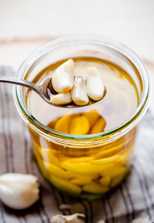 a spoon with some food in it on top of a glass jar filled with liquid