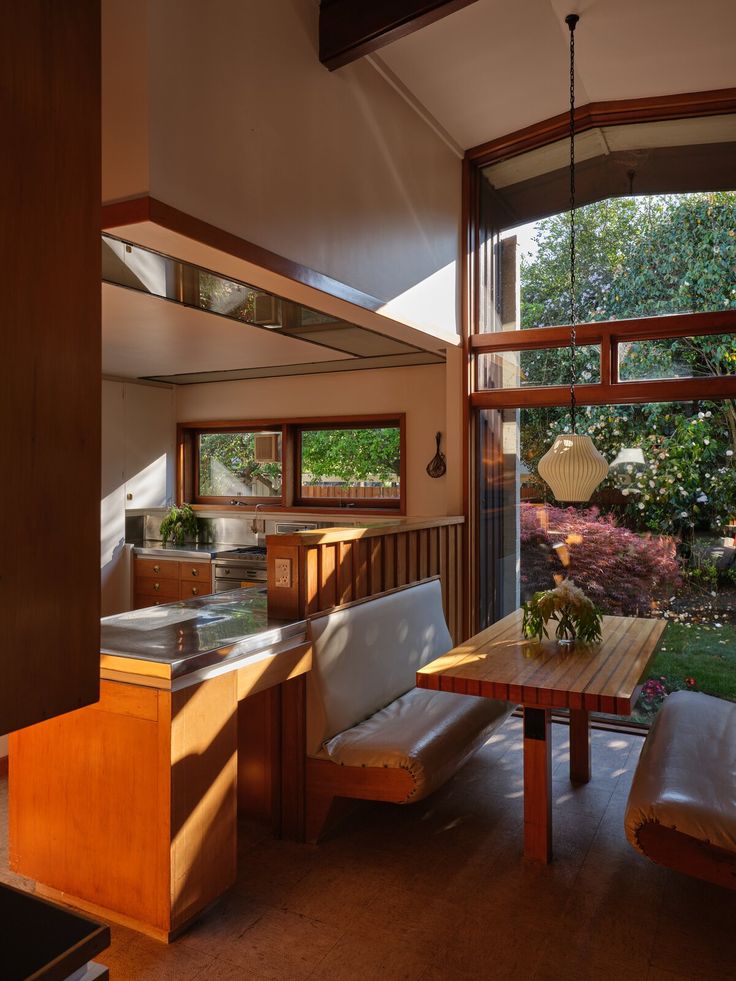 an open kitchen and dining room area with large windows on both sides of the house