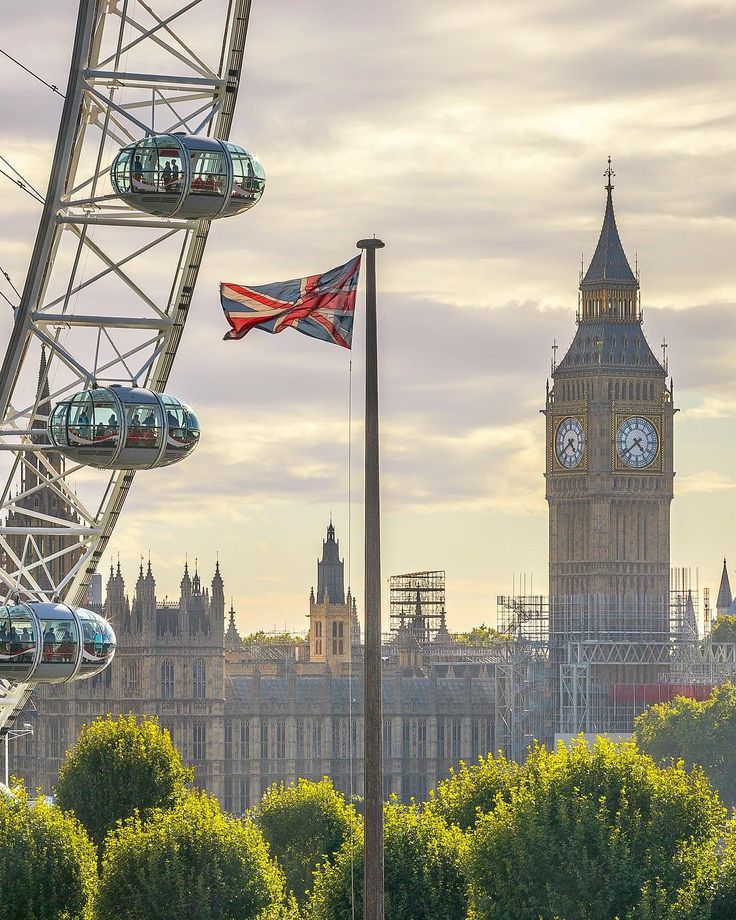 the big ben clock tower towering over the city of london, england with ferris wheel in foreground