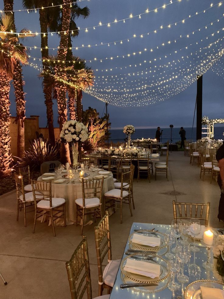 tables and chairs are set up for an event with string lights strung over the top