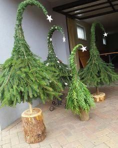 three christmas trees made out of branches sitting in front of a building with white stars on them