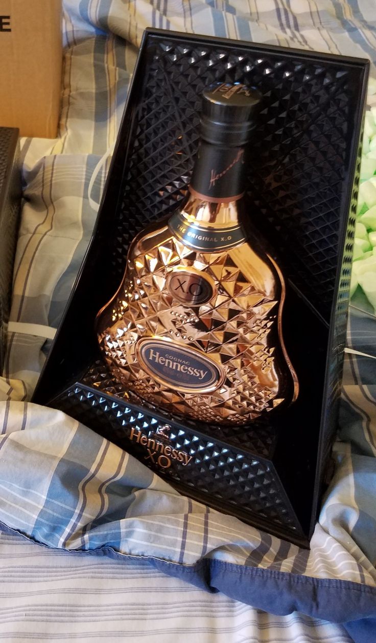 a bottle of perfume sitting in a box on top of a bed