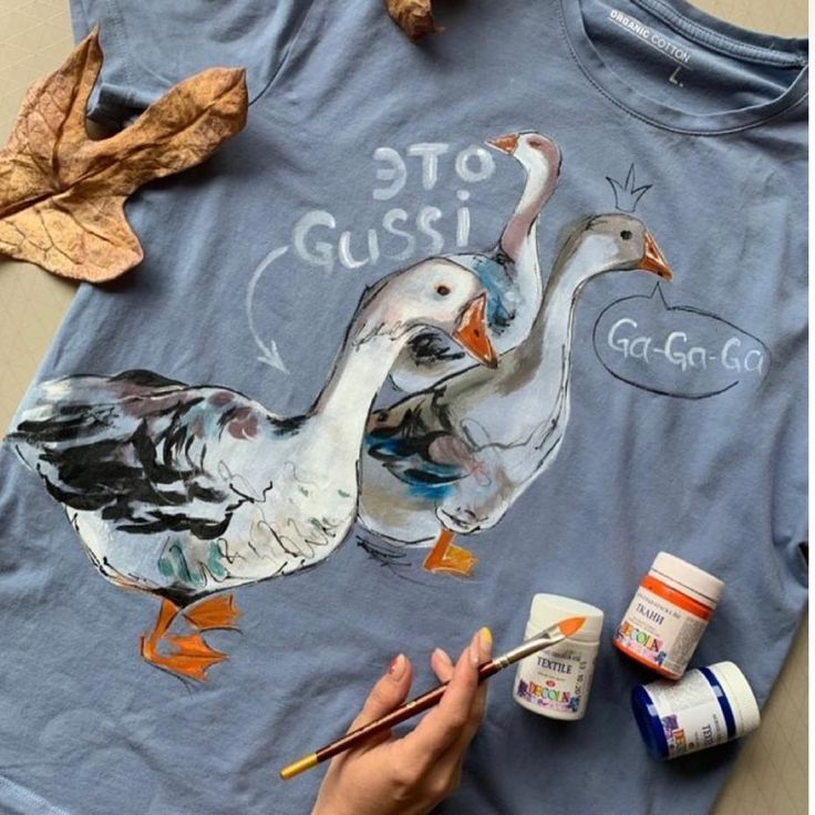 someone is painting two ducks on a t - shirt with acrylic paintbrushes