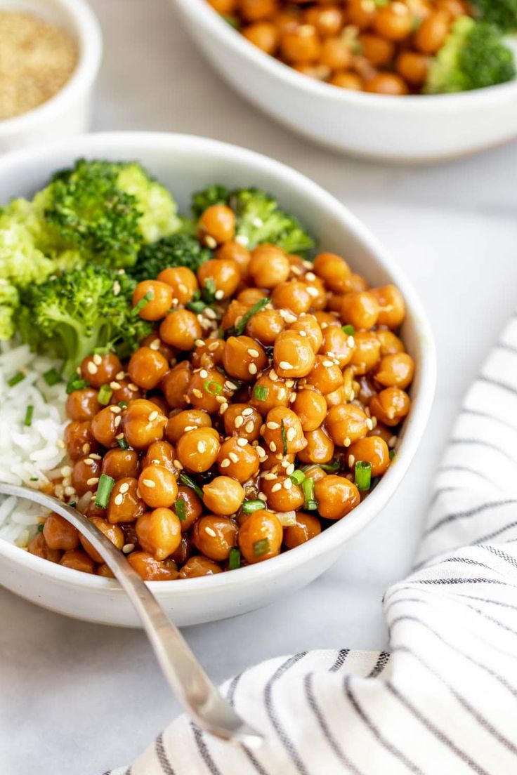 two bowls filled with broccoli and chickpeas on top of white rice