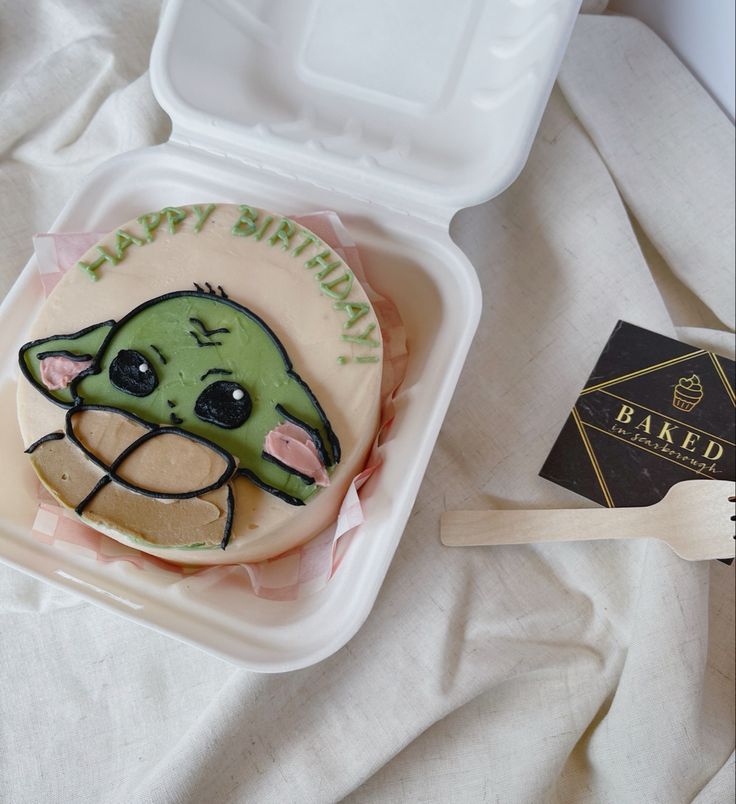 a star wars themed birthday cake in a plastic container with a wooden spatula next to it