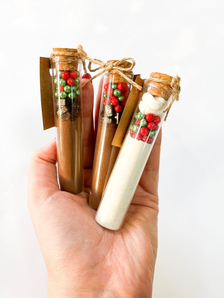 hand holding three cinnamon spice bottles with christmas decorations on them