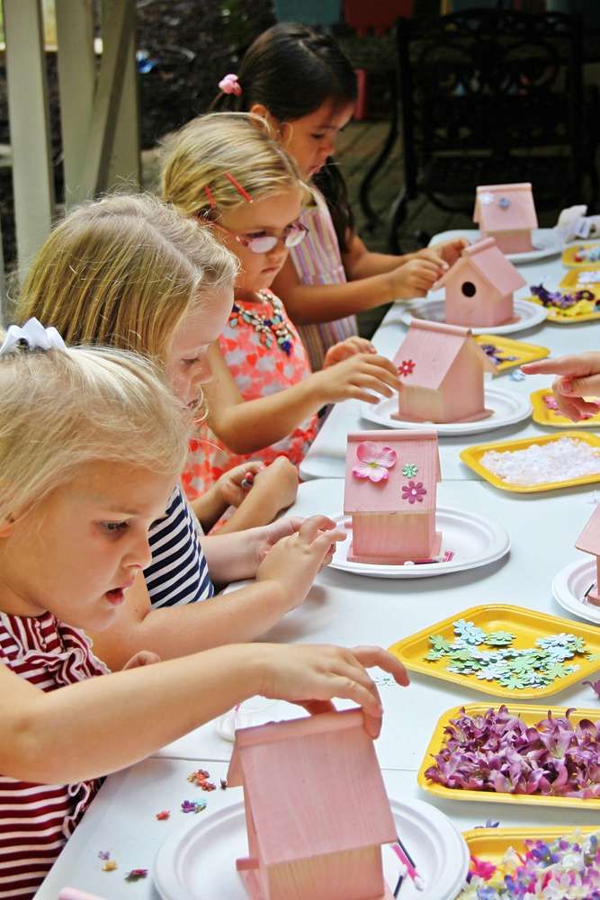 several children are sitting at a table with paper plates and pink houses on them,