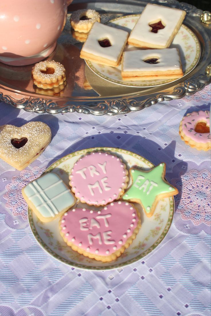 some cookies and pastries on a table with a pink teapot in the background