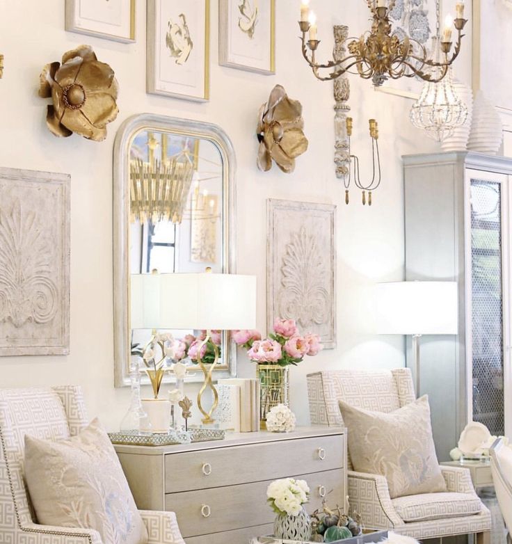 a living room filled with white furniture and lots of pictures on the wall above it