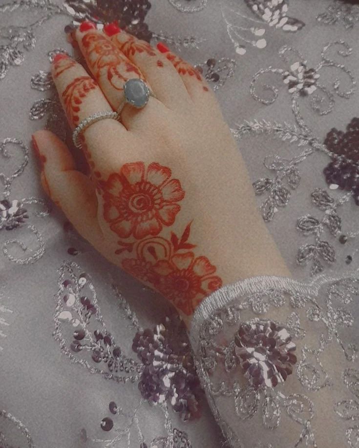 a woman's hand with henna and ring on top of her finger, covered in lace