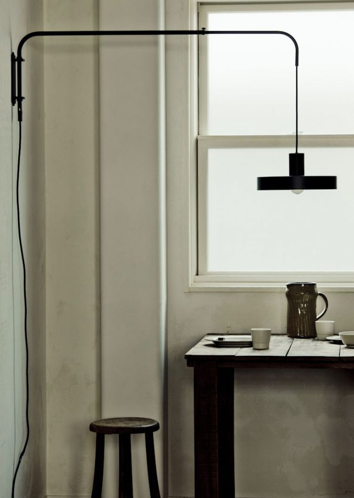 a room with a table, stools and a lamp on the wall next to it