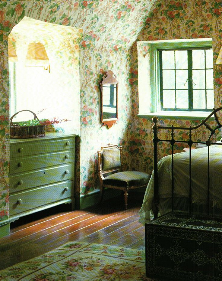 a bedroom with floral wallpaper and green dresser next to bed in the middle of it