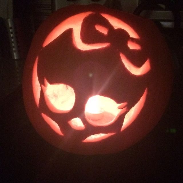 a carved pumpkin with an image of a cat on it's face in the dark