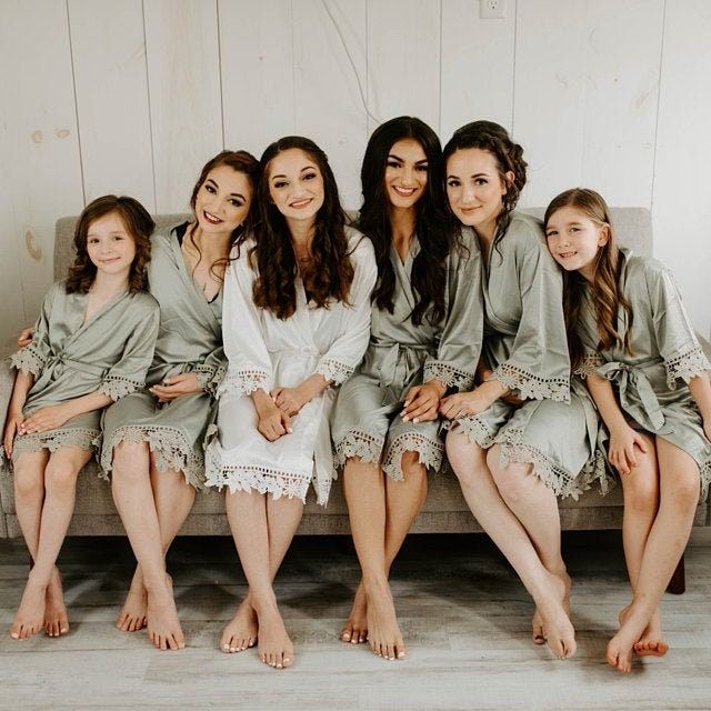 a group of women sitting next to each other on top of a couch in robes