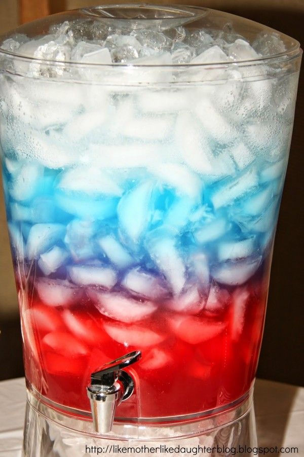 a red, white and blue drink in a tall glass with ice on the rim