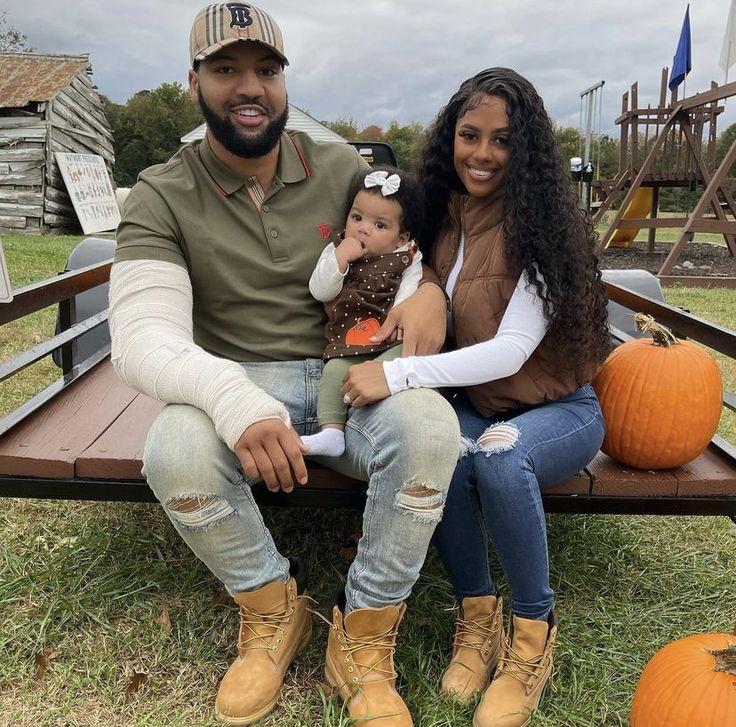 a man, woman and child sitting on a bench with pumpkins in the background