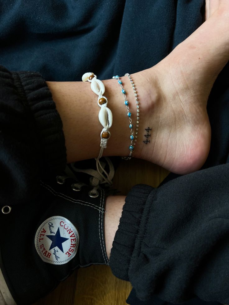 a woman's feet with two bracelets on her ankles and one has a star charm