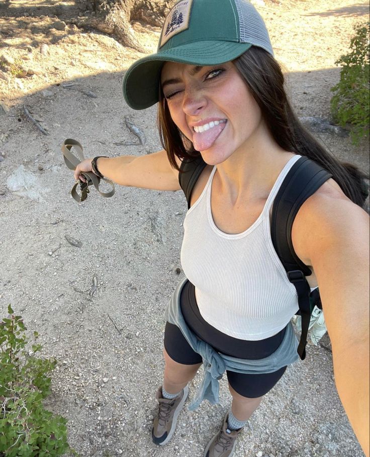 a woman with a baseball cap and knee braces holding a snake in her right hand